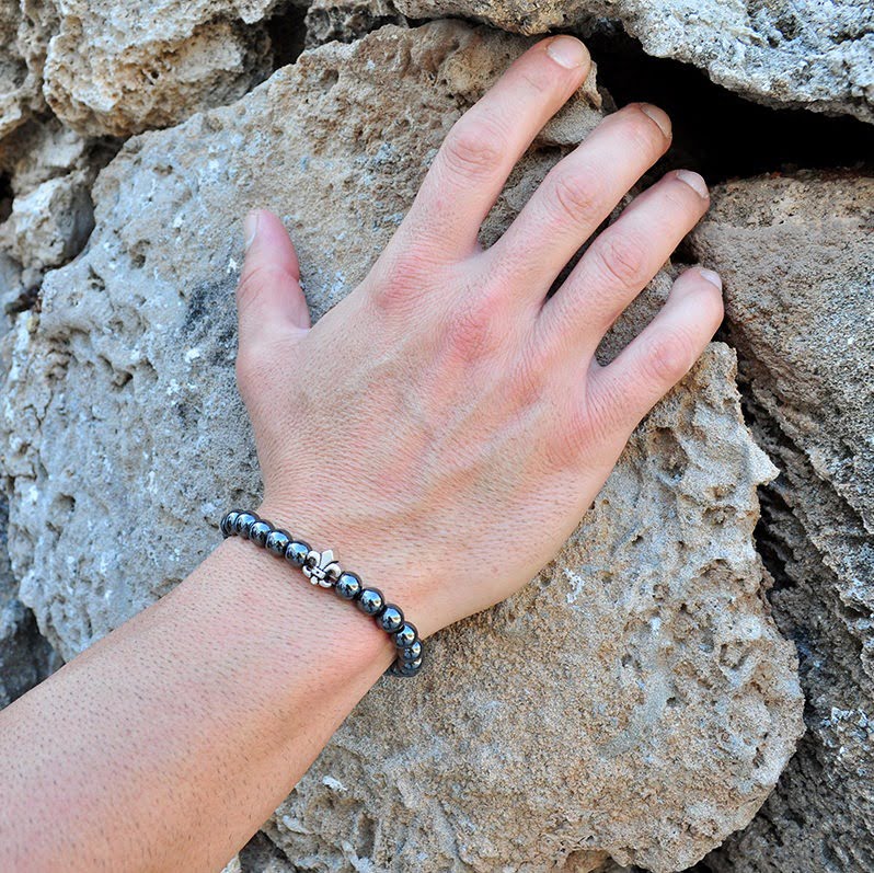 Χειροποίητο βραχιόλι με αιματίτη και επάργυρο Fleur De Lis, φτιαγμένο με ελαστική σιλικόνη για να προσαρμόζεται σε κάθε μέγεθος καρπού.