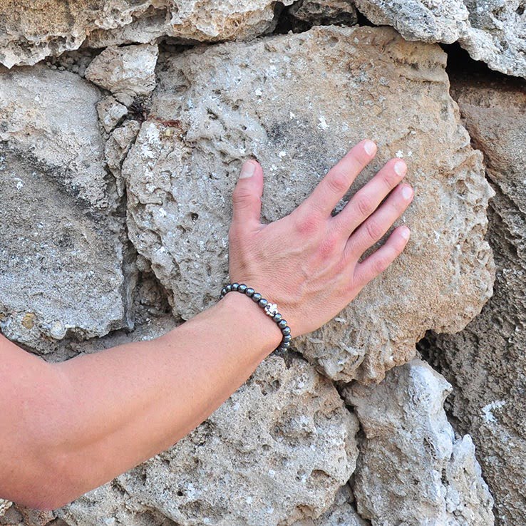 Χειροποίητο βραχιόλι με αιματίτη και επάργυρο Fleur De Lis, φτιαγμένο με ελαστική σιλικόνη για να προσαρμόζεται σε κάθε μέγεθος καρπού.